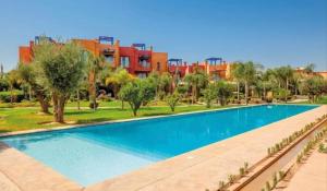a large swimming pool with trees and buildings in the background at Appartement Au vizir avec Accès au Parc de loisirs in Dar Caïd Layadi