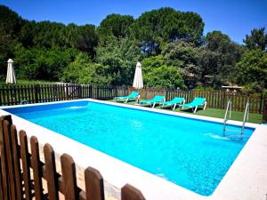 a swimming pool with blue chairs and a fence at El Andén del Hueznar in Constantina +17 photos