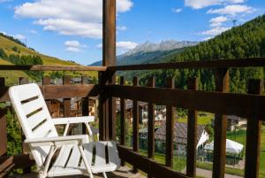 a white chair sitting on a porch with a view at Hostdomus - Casa Borgata in Borgata Sestriere