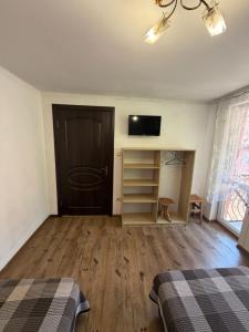 a bedroom with two beds and a tv on the wall at Zatishok Guest House in Rakhiv