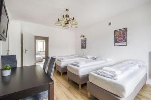 a room with three beds and a table and a dining room at Labo Apartment - apartamenty Plac Konstytucji in Warsaw
