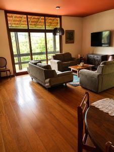 a living room with two couches and a tv at Quarto Imbuí in Teresópolis