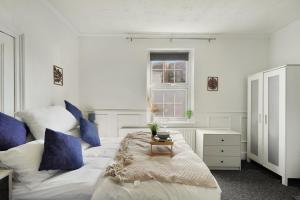 a bedroom with a large white bed with blue pillows at Garden Flat In Watford in Watford West Station
