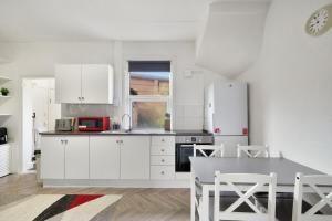 a kitchen with white cabinets and a table with chairs at Garden Flat In Watford in Watford West Station