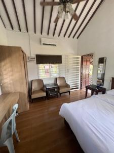 a bedroom with a bed and two chairs and a table at Wadi Al Hasyer Homestay Daisy in Juasseh
