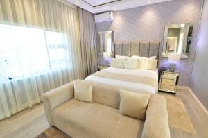a bedroom with a large bed and a couch at Sparrow Boutique Hotel in Bulawayo