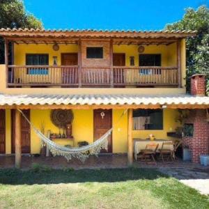a yellow house with a porch and a balcony at Hostel e Suites Caminho do Vale in Palmeiras