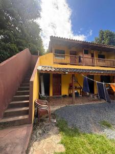 a yellow house with a staircase and a balcony at Hostel e Suites Caminho do Vale in Palmeiras +6 photos