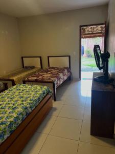 a bedroom with two beds and a door to a yard at Hostel e Suites Caminho do Vale in Palmeiras
