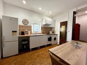 a kitchen with white cabinets and a table and a clock at L'essentiel Gare d'Oullins - 3 chambres - 15 min de Lyon in Oullins