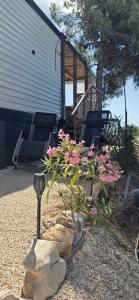 a garden with flowers and rocks and a house at Mobile home Bokun sriće in Drage