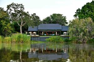 a house sitting on the water next to a lake at Mukwa River Lodge in Livingstone