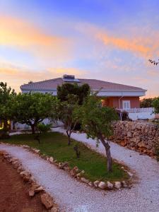 a house with a stone wall and trees in front at Villa Chimera in Pachino