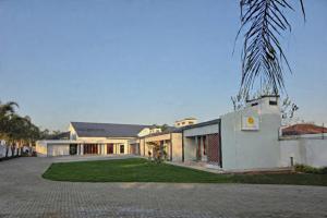 a large white building with a palm tree in front of it at Black Villa Lodge in Hammanskraal