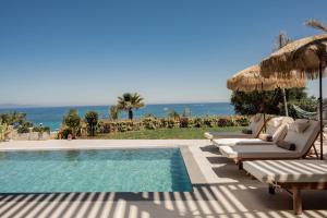 a pool with chairs and an umbrella and the ocean at Callisto Azzure in Zakynthos