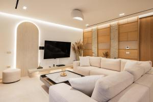 a living room with a white couch and a tv at Callisto Azzure in Zakynthos