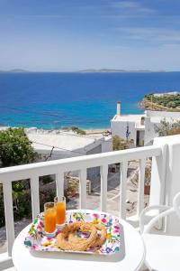 a table with a plate of food and two glasses of orange juice at Aegean View Suites Mykonos in Agios Stefanos