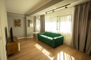 a living room with a green couch and a window at Oliv Residence in Iaşi