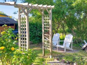 two white chairs sitting under a wooden pergola at Bungalow Koje in Kröslin