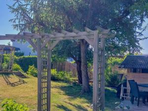a wooden pergola in a yard with a tree at Bungalow Koje in Kröslin +21 photos