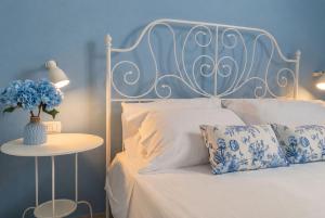a bedroom with a white bed with a vase with blue flowers at Domus Rubra in Castelsardo