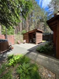 a backyard with a wooden cabin in the woods at Chata przy lesie - sauna i balia in Łuka