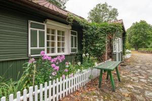 a green bench in front of a house with flowers at Malowniczy Dom nad samą rzeką, z pięknym widokiem in Litwinki