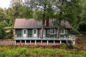 a green house on a hill with trees at Malowniczy Dom nad samą rzeką, z pięknym widokiem in Litwinki