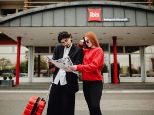 a man and a woman looking at a newspaper at Ibis Budapest Citysouth in Budapest