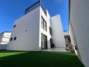 a white house with a green lawn in front of it at Guest House Gabi in Srima