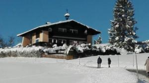 zwei Menschen stehen im Schnee vor einem Haus in der Unterkunft Ferienhaus Marianne in Abtenau