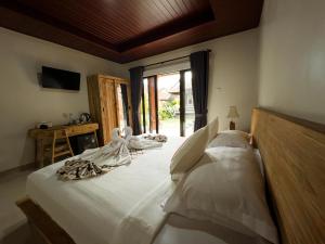 a bedroom with a bed with white sheets and a window at JERO Tabola 2 in Sidemen