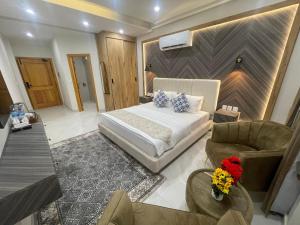 ein Schlafzimmer mit einem Bett, einer Couch und einem Stuhl in der Unterkunft Hotel Naim Wakeel in Islamabad