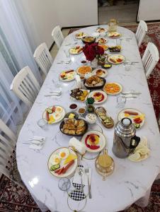 a white table with plates of food on it at Cholpon Guest House & Hostel in Toktogul