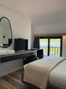 a bedroom with a bed and a desk with a mirror at Lumi i Bardhe Hotel & Restaurant in Kuç +15 photos