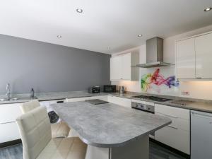 a kitchen with white cabinets and a large marble table at 38 The Parade in Walton-on-the-Naze