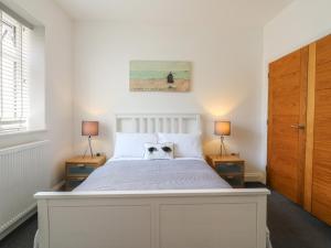 a bedroom with a white bed with two lamps at 38 The Parade in Walton-on-the-Naze