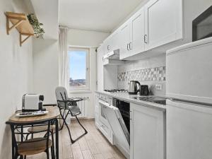 a kitchen with white cabinets and a table and chairs at Konstanzer 103 - 2 Room Ap & Parking- Iulius Mal - Smart TV - Highspeed Wi-Fi in Iaşi