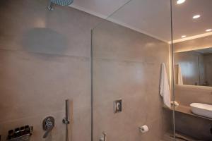 a bathroom with a glass shower with a sink at Aegean View Suites Mykonos in Agios Stefanos +23 photos