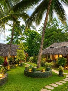 a garden with palm trees and a resort at Nature Lounge in Udawalawe
