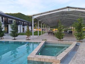 a swimming pool with a patio and a building at Lumi i Bardhe Hotel & Restaurant in Kuç