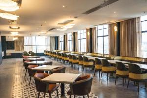 a dining room with tables and chairs and windows at Pride Plaza Indore in Indore