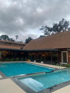 a large swimming pool in front of a building at DZION Resort Coorg in Gonikoppal