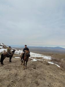 two people riding horses on a snow covered hill at Cholpon Guest House & Hostel in Toktogul