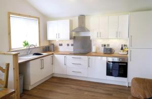 a kitchen with white cabinets and a white refrigerator at Blaen Cedi Holiday Cottages in Swansea +29 photos