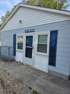 a white building with a door and a window at The Cottage in Dagsboro