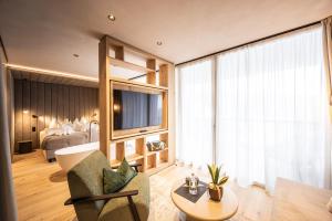 a living room with a couch and a tv and a bed at Alma Alpina Lodge, Adults Only in Obereggen +22 photos