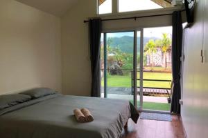 a bedroom with a bed and a large sliding glass door at หินผาปัว รีทรีต & หินผาโฮมสเตย์ in Ban Choko