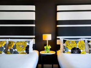 a bedroom with two beds and a night stand with a lamp at Mövenpick Hotel Auckland in Auckland
