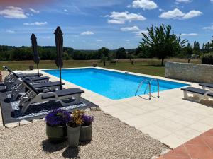 a swimming pool with lounge chairs next to at Petit Rousset Gite Noyer in Eymet